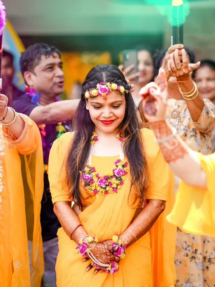 A colorful and happy moment as the bride is showered with blessings and good wishes, with color smoke adding to the festive vibe of the Haldi ceremony.