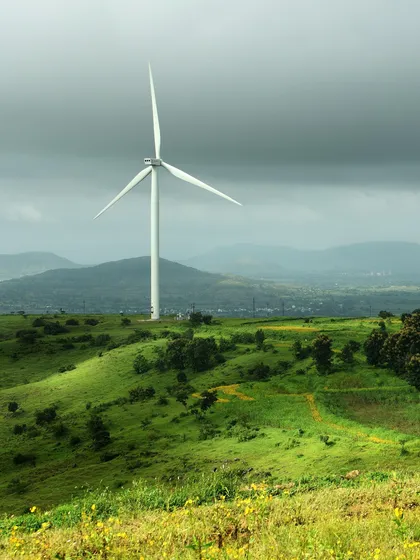 A classic scene from the monsoon season in Maharashtra. The contrast between the modern windmill and the timeless, rolling green hills under a dramatic sky tells a story of changing landscapes.