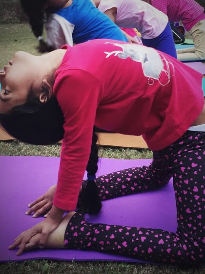 A young student demonstrates her flexibility in Ustrasana, the camel pose, at our kids' yoga day. We encourage children to explore their physical abilities with joy.