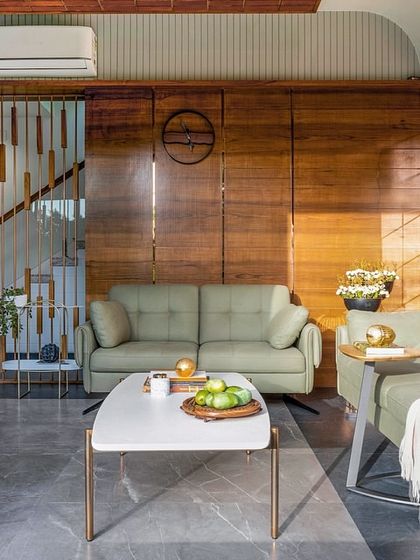 This wider view of the living space at Tranquil Mango Haven showcases the holistic spatial planning. The slatted wooden screen provides a subtle division for the staircase while maintaining an open feel, and the furniture is arranged to encourage both social connection and quiet reflection.