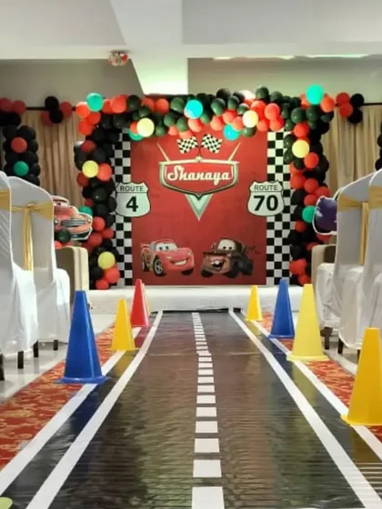 An immersive Cars themed party entrance. The aisle is designed like a road, leading to a backdrop featuring characters from the movie, perfect for a grand entry.