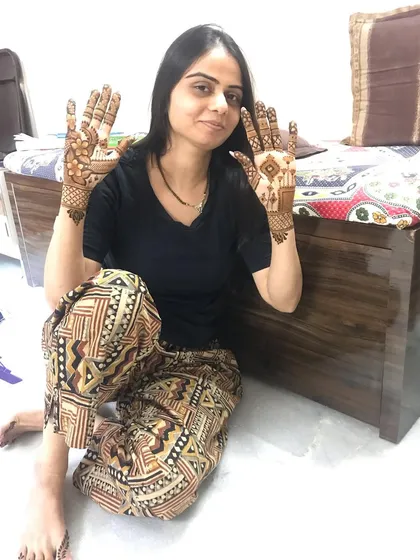 A happy client showing off her elegant party mehndi.