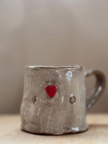 A student's first creation, this charmingly rustic mug with a bright red heart, shows the simple joy of making something with your own hands. It's perfectly imperfect and full of love.