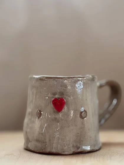 A close-up of the heart-stamped mug. The simple red heart against the rustic, textured glaze is so charming.