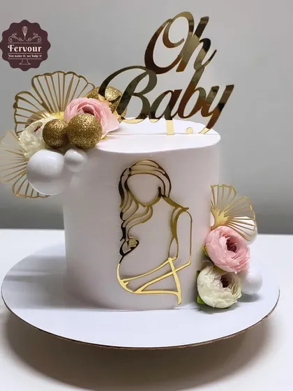 An elegant "Mom to be" cake in a clean white design. This chocolate Oreo cake is decorated with gold accents, delicate flowers, and a stylish topper.