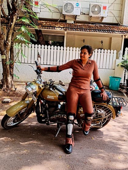 A graduate poses with her bike, showcasing her confident posture and stylish gear. She is a role model for future riders.