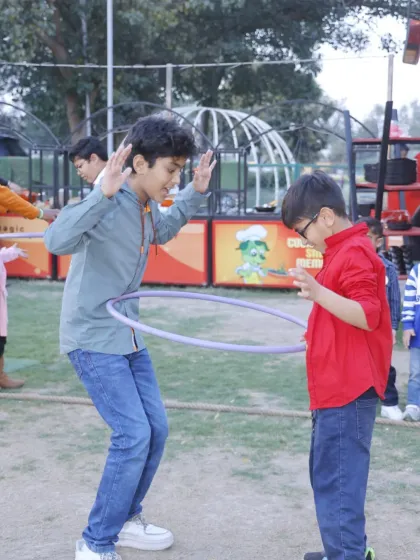 Fun and games in the open air. Two boys enjoy a hula hoop challenge during an outdoor event at our Punjabi Bagh club.