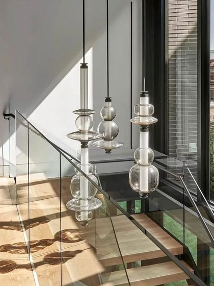 Luna pendants are installed along a staircase, their vertical orientation accentuating the height of the space and creating a cascading light effect.