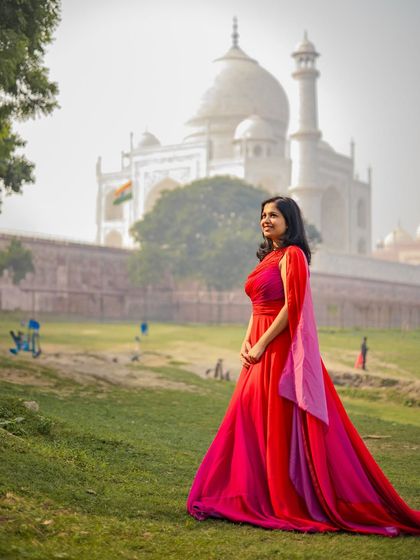 A beautiful solo shot of the bride in a flowing red gown, with the magnificent Taj Mahal in the background.