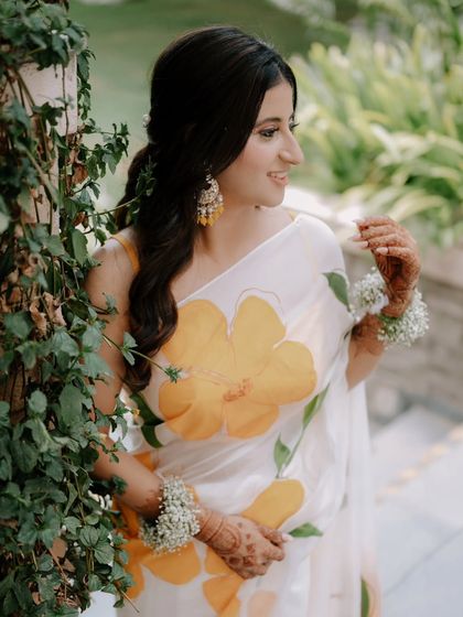 A lovely, candid portrait of the bride during her Haldi ceremony. Her hand-painted saree and floral jewelry create a fresh and unique look.