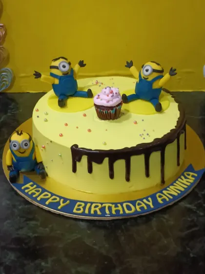 A fun Minions-themed cake. This bright yellow cake is decorated with playful fondant Minions and a chocolate drip.