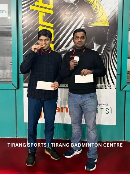 Two winners proudly showing their medals and prize money.