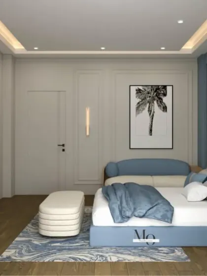 A beautiful bedroom in shades of blue and white. The design includes a comfortable sofa, a stylish ottoman, and a TV unit with integrated shelving, making it a complete living suite.