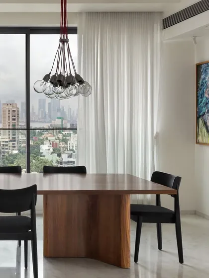 Overlooking the city, this dining space is designed for both intimate meals and entertaining. The solid wood table provides a grounding element, while the modern cluster pendant light adds a touch of contemporary design.