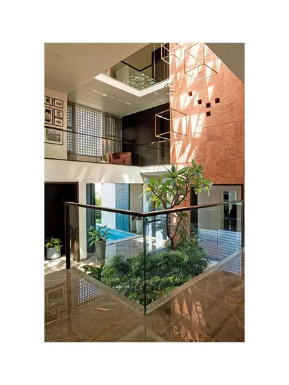 An internal courtyard in the Notan Home, designed as a private oasis that brings light, air, and nature into the center of the house. This multi-level view shows the interplay between the water body, the indoor planter with a frangipani tree, and the living spaces above, creating a constant visual connection across the home.