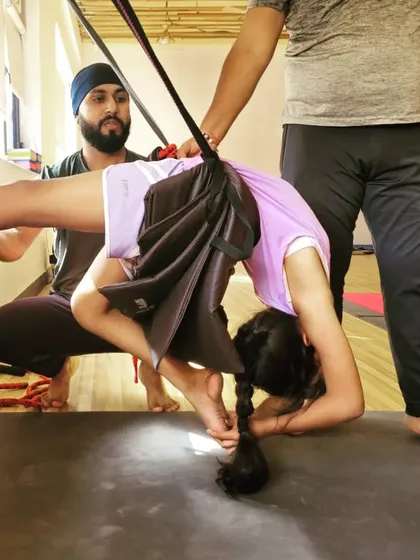 I am guiding a young student through a deep forward bend using a prop for support. It is wonderful to see the benefits of yoga at any age.
