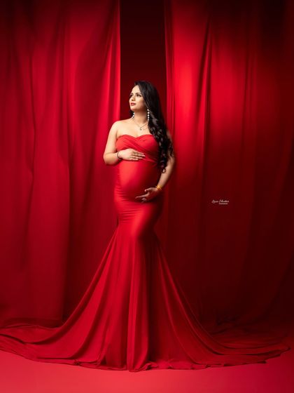 This portrait highlights the beautiful fit of the red mermaid gown, celebrating the pregnant form with grace and style.