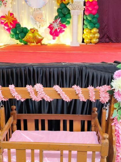 A close-up of the decorated wooden cradle for the christening ceremony, adorned with pink and white floral arrangements.