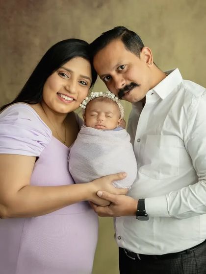 A classic family portrait with a beautiful studio backdrop, capturing the family's first photo with their new baby girl.