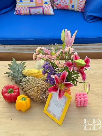 Another unique table arrangement from the carnival event, combining lilies, pineapples, corn, and bell peppers. The design is eclectic, colorful, and sustainably chic.