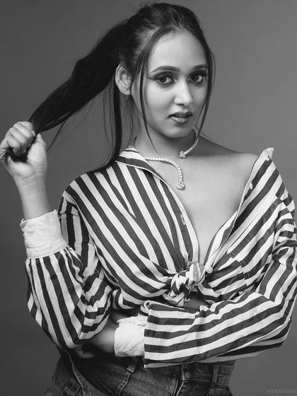 A black and white portrait of a model in a striped shirt, with a moody and editorial feel.