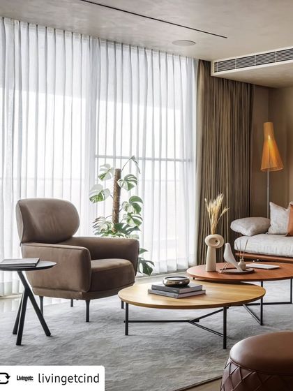 A detail shot of the living area, focusing on the soft textures and modern furniture. Sheer curtains diffuse natural light, creating a calm and airy atmosphere that is central to the home's design.
