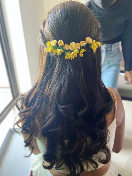 Another view of this lovely Haldi hairstyle. The soft curls and fresh flowers create a romantic and feminine look.