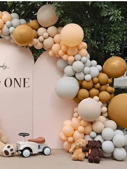 A chic and modern 'Baby is One' birthday setup with a neutral color palette of beige, brown, and white balloons.