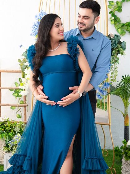 The couple shares a loving look, framed by the golden birdcage and lush greenery. This portrait feels like a scene from a romantic fairy tale.