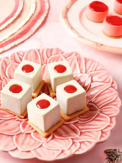 These bite-sized strawberry mousse cubes are arranged on a beautiful pink plate, creating a delicate and artistic dessert photo.