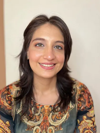 A happy client showing off her fresh and dewy makeup. The subtle orange tones on the eyes and the glossy lip create a warm, approachable look.