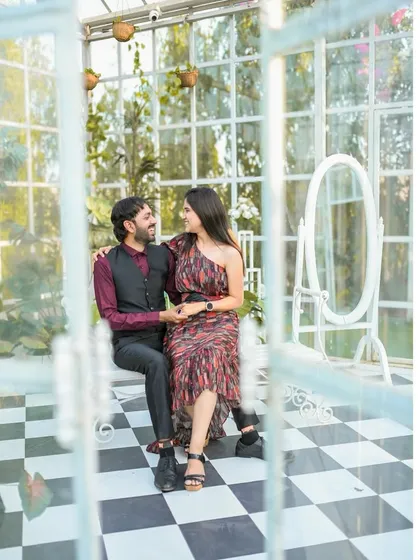 A lovely portrait of the couple seated inside the glasshouse, framed by the window panes for an artistic effect.