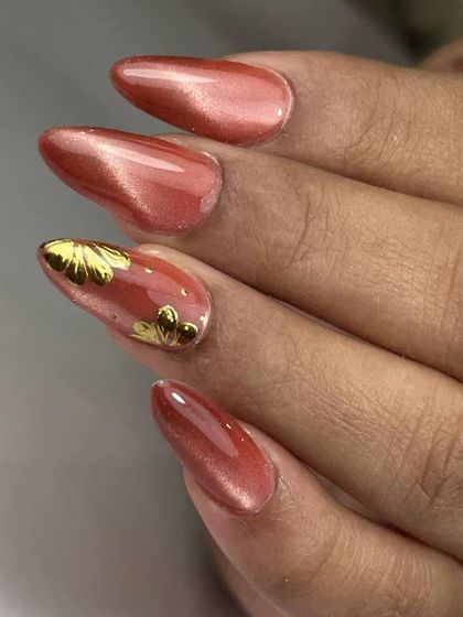A peachy-pink cat-eye manicure with delicate gold floral accents. The combination of the shimmery base and metallic details is soft and romantic.