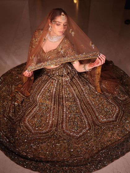 A top-down shot of the model seated in the antique gold lehenga, showing the incredible volume and detail of the skirt.