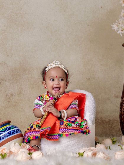 A smiling baby Radha sitting contentedly in a mini armchair, surrounded by props. This shows how I create a comfortable and engaging environment for the little ones.