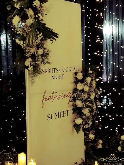 A chic and personalized welcome sign for the cocktail night, set against a backdrop of twinkling lights.