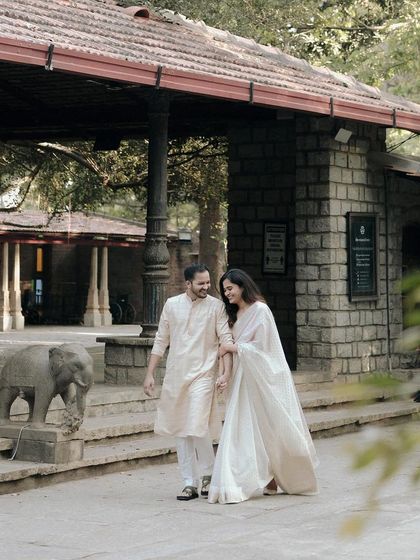 A couple strolls along a path, the stone architecture and greenery creating a feeling of being in a private, historic estate.