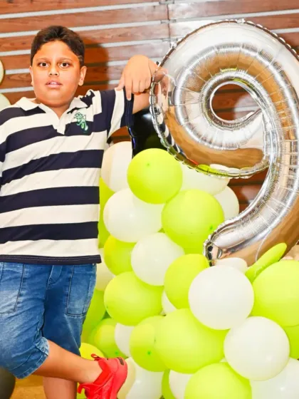 The birthday boy posing with a giant '9' balloon at his Arsenal-themed party. We use props like these to create fun photo opportunities.