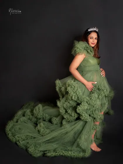 A profile shot that shows the magnificent tiered gown in all its glory. Wearing a tiara, she looks every bit the queen of her growing family.