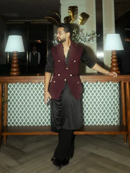 Another angle of the modern Diwali ensemble, showing the sharp tailoring of the burgundy waistcoat and the fluid drape of the black kurta.