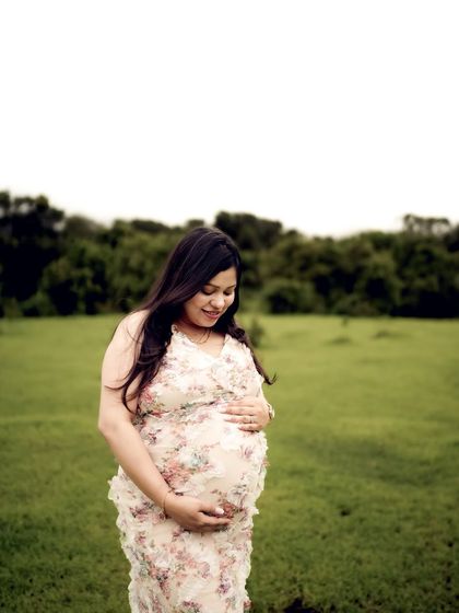 A serene portrait of the mom-to-be looking down at her bump in a green field. The soft light and her gentle expression create a peaceful mood.