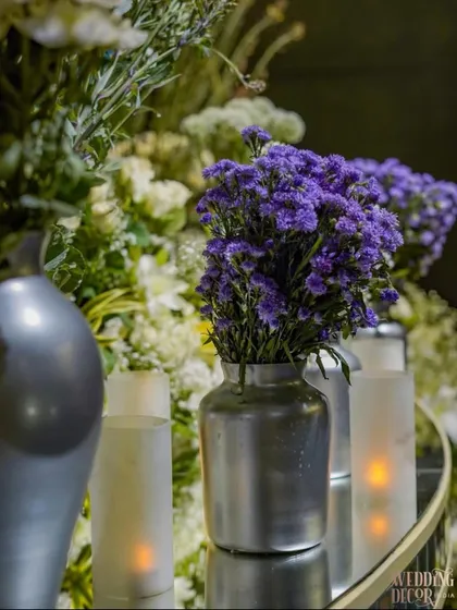A close-up of a floral arrangement in a silver vase, featuring deep purple flowers. This shows the color accents I used to complement the dominant blue theme.