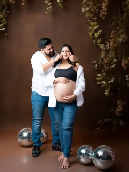 A fun and playful maternity shoot with a touch of sparkle. The couple shares a cute moment surrounded by disco balls, adding a unique and modern twist to their portraits.