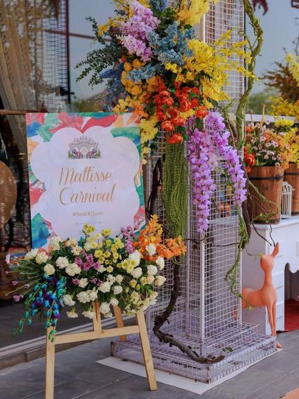 A beautiful welcome sign for a "Matisse Carnival" themed event. The sign is surrounded by a spectacular arrangement of multi-colored flowers, setting an artistic and vibrant tone.