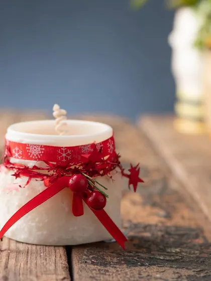 A simple and sweet white jar candle, decorated with a festive red ribbon for a touch of Christmas cheer.