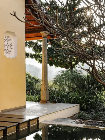 A beautifully lit shot of the villa exterior at Dvara Resorts, capturing the warm morning light. The image highlights the traditional architectural details and the serene, natural surroundings.