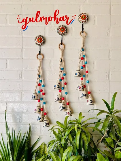 Our 'Symphony Chimes' in the 'Gulmohar' color variant, featuring red and blue wooden beads. These chimes are a beautiful combination of macrame knots and hand-painted ceramic bells, perfect for any decor style.