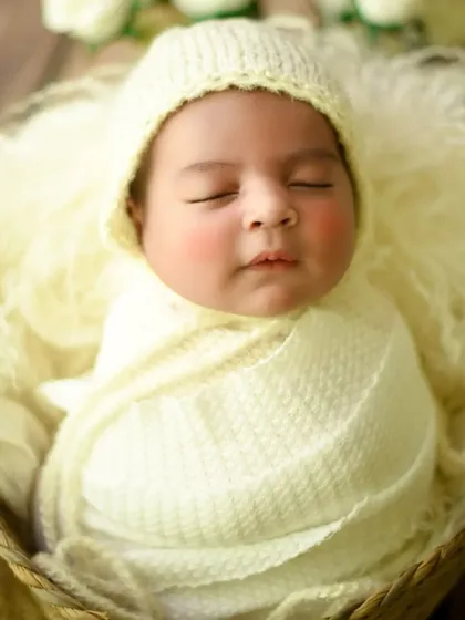 A simple and sweet portrait with a cream-colored knit bonnet, focusing on the baby's rosy cheeks.