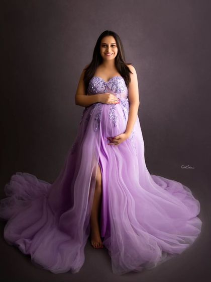 A sweet and happy portrait. This mom-to-be is smiling brightly in her beautiful lavender gown, looking straight at the camera.