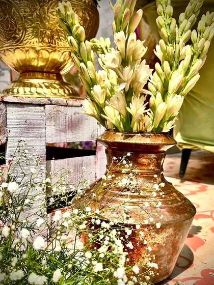 Close-up of decor details, with tuberoses in a rustic brass pot, adding a touch of traditional fragrance and beauty.